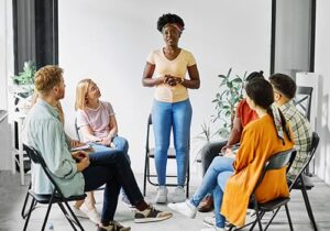 People sitting in a circle with someone standing up to share in an intensive outpatient program