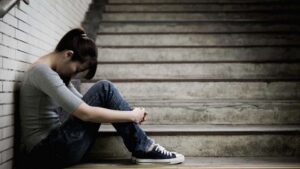 does Adderall cause depression? A woman sits at the bottom of the stairs thinking of the answer