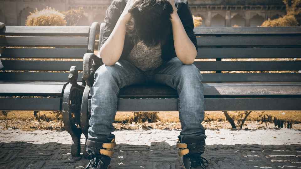 Signs of Cocaine Addiction hero image of a man sitting on a bench struggling with addiction.