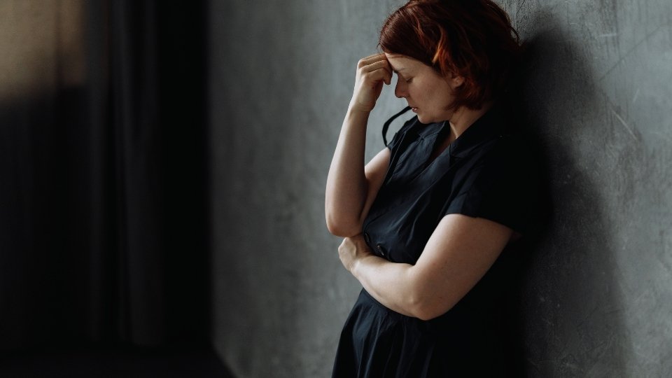 Depression and Alcohol hero image of a woman leaning against a wall while depressed.