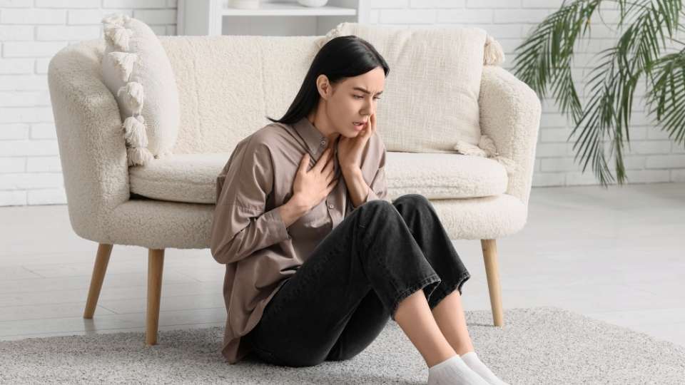 Panic Attack Physical Symptoms hero image of a woman sitting on the ground.